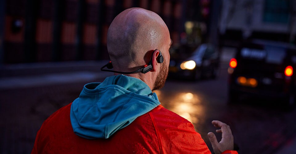 nyitott fülű fejhallgatót viselő férfi egy zsúfolt utcán