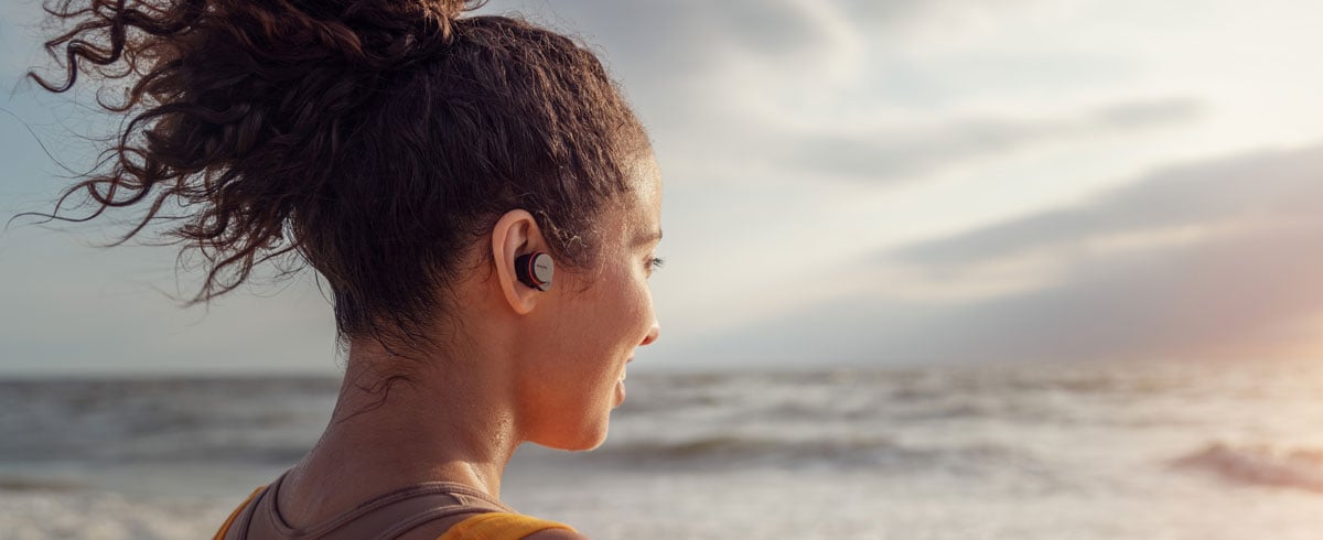 Egy nő valódi vezeték nélküli fejhallgatót visel a tengerparton