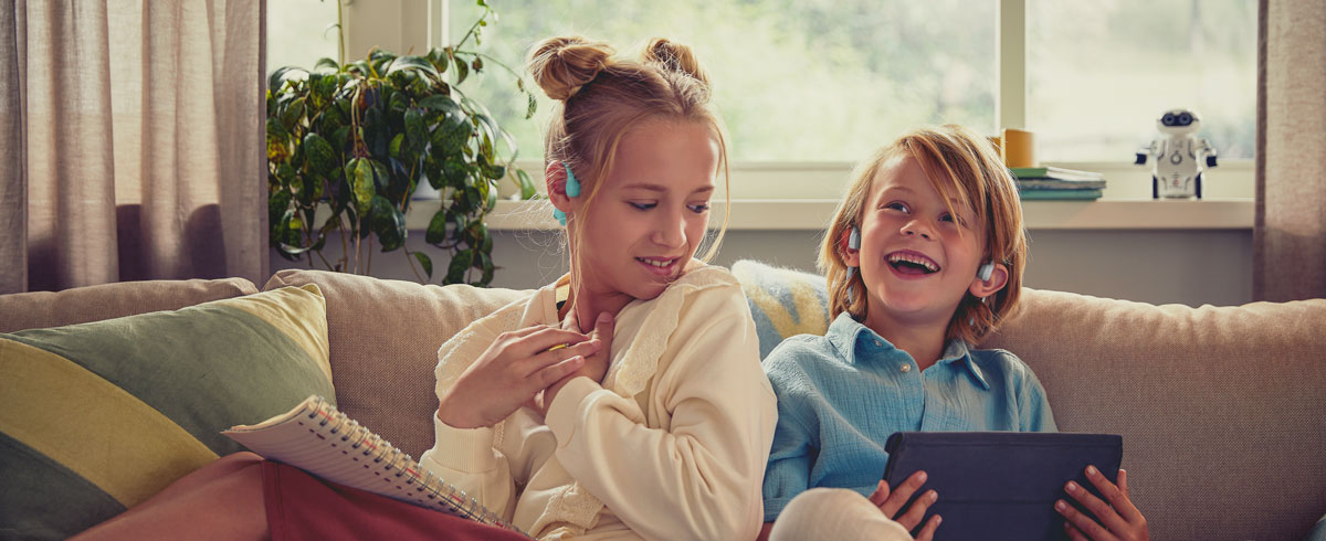 Philips open-ear kialakítású gyermek fejhallgatót használó, videót néző gyerekek