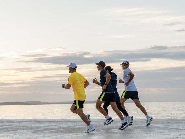 A futás négy résztvevője együtt fut a vízparton.