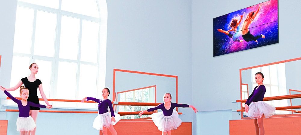 Digitális Signage kijelző a falon. Gyerekek tanulnak balettozni egy teremben